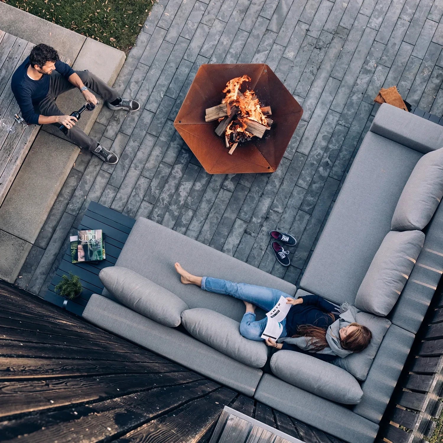 Höfats TRIPLE 120 Fire Pit in Corten Steel with burning logs, placed on a white surface.