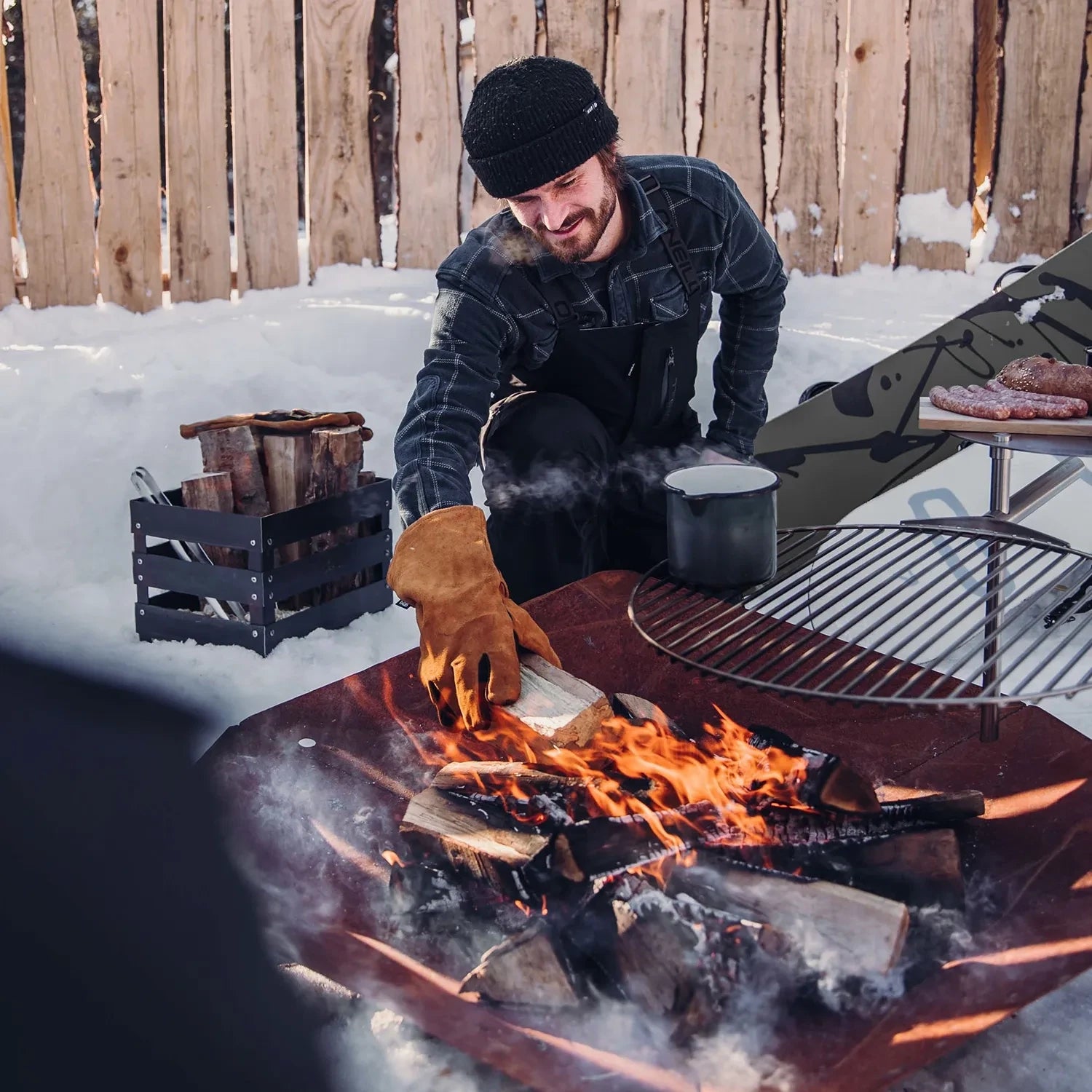 Höfats TRIPLE 120 Fire Pit in Corten Steel with burning logs, placed on a white surface.